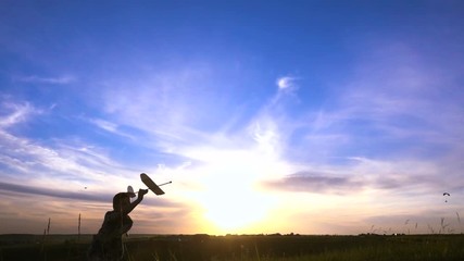 Silhouette of boy running with airplane against sunset