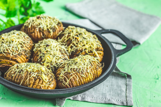 Baked potatoes in black frying pan with pesto sauce