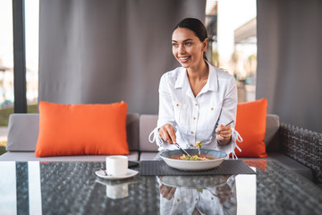 Smiling woman having meal in the cafe and looking away