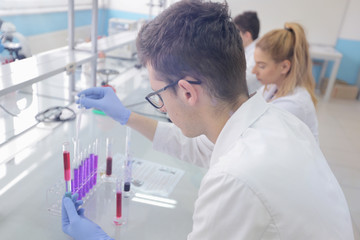 Fototapeta premium Group of young Laboratory scientists working at lab with test tubes and microscope, test or research in clinical laboratory.Science, chemistry, biology, medicine and people concept.