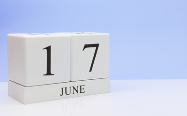 June 17st. Day 17 of month, daily calendar on white table with reflection, with light blue background. Summer time, empty space for text