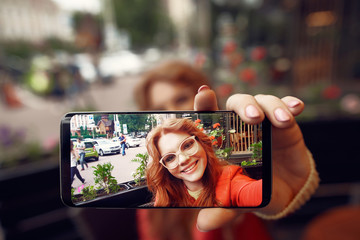 Beautiful red-haired girl making selfie and smiling