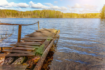 Fishing tourism relax concept. Traditional Russian Finnish and Scandinavian view. Beautiful forest lake or river on sunny summer day and old rustic wooden dock or pier. Fishing bridge on morning lake