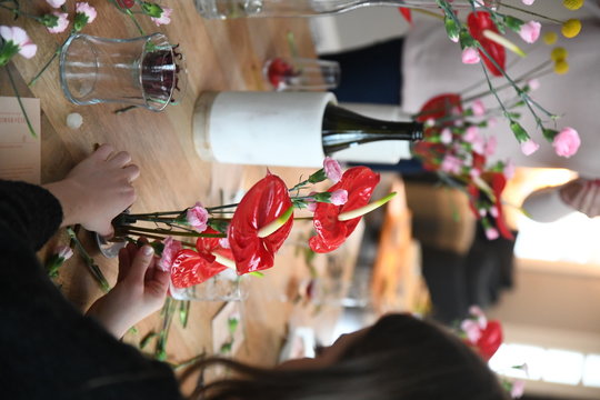 Woman makes floral arrangements with peace lilies and carnations