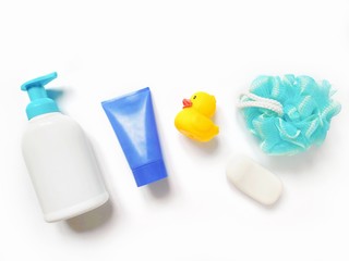 Flat lay bath products photo. Liquid soap packaging, purple cream tube, yellow rubber duck, blue sponge and soap bar. Items for personal care, natural organic cosmetics