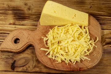 Grated cheese on cutting board on wooden table