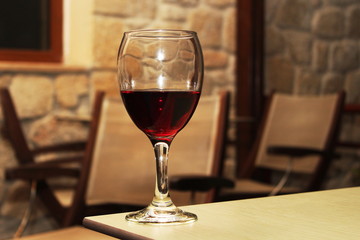 Glass of tart gourmet red wine on edge of table. Selective focus.
