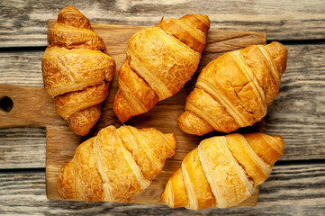 croissants on wooden cutting board, on background wood top view