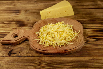 Grated cheese on cutting board on wooden table