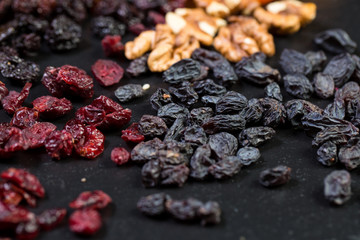 Fototapeta premium Theme is a sweet dessert made from natural products without sugar. Macro close up closeup dessert dried fruit set of walnut, cherry and cranberry raisin fig honey and sesame and flax seeds