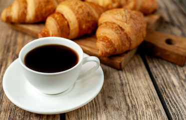 Obraz na płótnie Canvas coffee and croissants on wooden cutting board, on wooden background