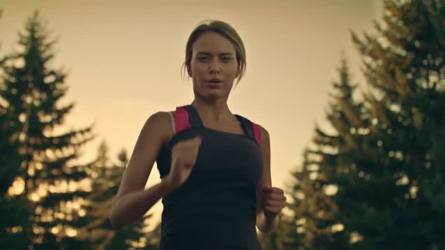 Sport woman running in park at sunset. Tired runner stop for break at park road