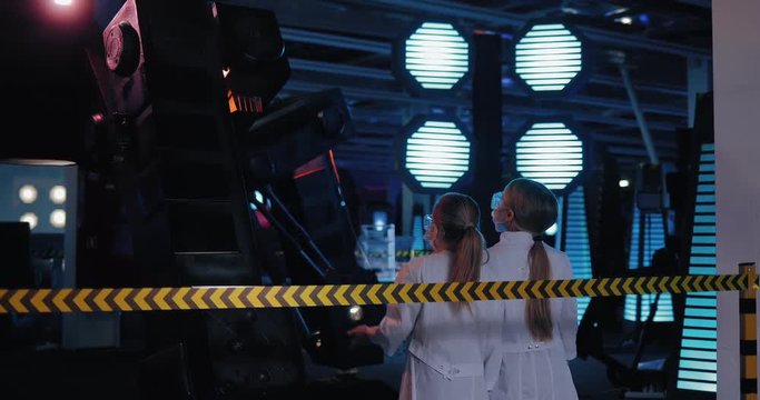 Young scientists are looking at a technical installation with a robot. Laboratory technicians discuss ideas in the space laboratory.