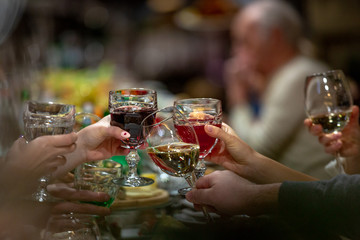 People clinking glasses above reataurant dinner table at some festive occasion. Drinking toasts and clinking tumblers at a dinner party.