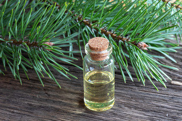 A bottle of pine essential oil with pine branches