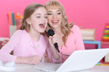 Portrait of cute girl sitting at table and singing karaoke