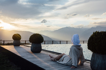 Woman relaxing at the poolside, wearing bathrobe and turban