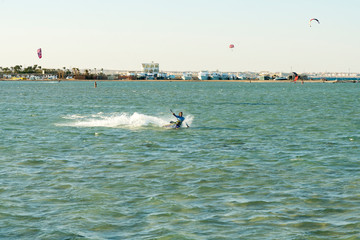 Kitesurfing Kiteboarding action photos man among waves quickly goes. A kite surfer rides the waves. lens illumination