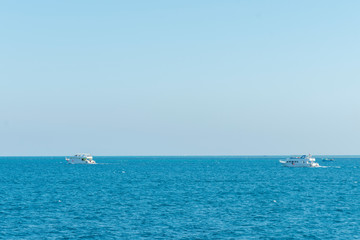 Fototapeta premium Tourist ship sailing in ocean. shipping business tourism concept. Background. Blue sea, pink sky at dawn and a white ship on the horizon. Concept of rest, vacation, weekend and cruise