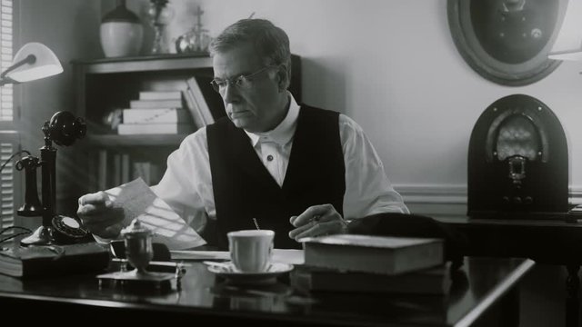 1929 businessman looking at stock market quotes during the crash while sitting in his office