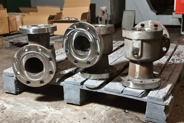 Factory production of taps and valves for water and gas. Three future valves lie on a wooden panel and wait in line for processing on the machine to create a screw in the holes for assembly