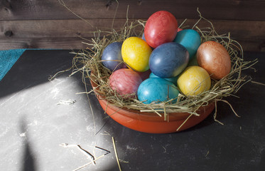 Easter eggs in a nest with hay on a wooden table