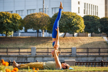 Couple of young man and woman practicing acro yoga