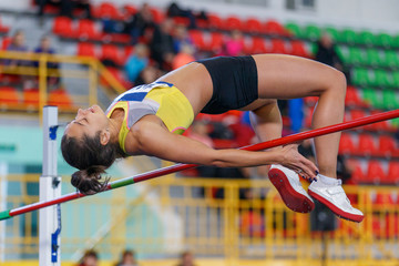 Professional female athlete jumping over bar