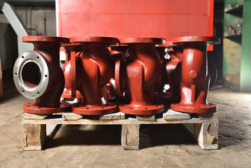 Iron or cast iron pipes, bases for creating valves, lie on a wooden panel before further processing...
