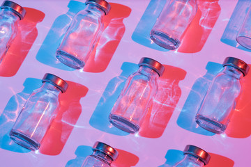 Glass bottle for vaccination with color lighting. Conceptual photo about the danger of viral diseases. - obrazy, fototapety, plakaty
