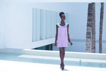 Attractive black woman wearing pink fringed dress walks the runway