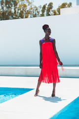 Attractive black woman wearing coral fringed dress walks the runway