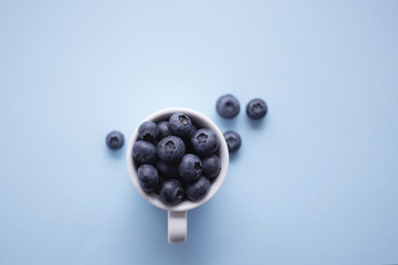 White cup of juicy blueberries. Top view. Sot selective focus. Healthy eating concept