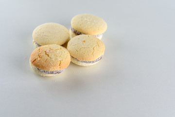 Delicious Argentinian cookies alfajores with cream dulce de leche close-up on the table. White vanilla macaroons on wooden background. French delicate dessert for Breakfast in the morning light.