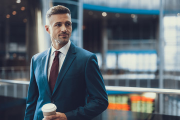 Man standing in airport with beverage in hand