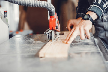 A man carves a tree. The carpenter works in a studio. An engineer provides a tree shape