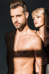 young woman hugging handsome shirtless man with shadows on torso