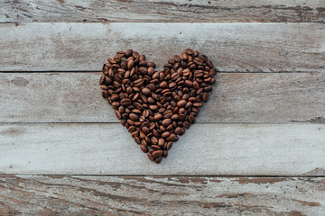 Coffee beans in shape of heart on wooden background