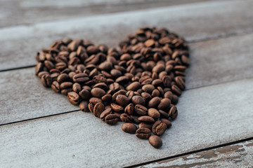 Coffee beans in shape of heart on wooden background