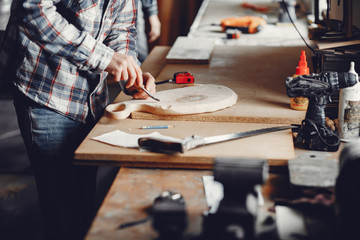 Obraz na płótnie Canvas A man carves a tree. The carpenter works in a studio. An engineer provides a tree shape