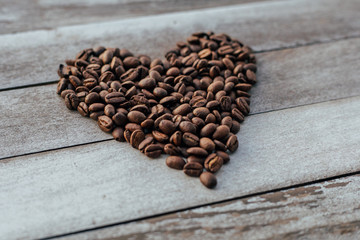 Coffee beans in shape of heart on wooden background