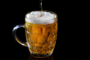 Light beer in a glass on a black background