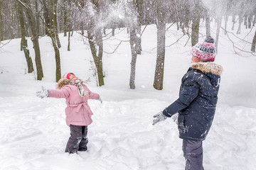 Children are playing snowballs in the street in the park in the open air.