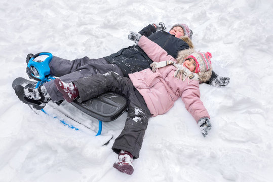 A happy boy and girl lying together in the snow, making snow angels.