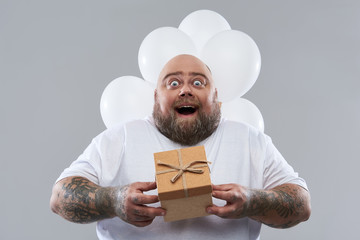 Excited man holding his present and having balloons behind him