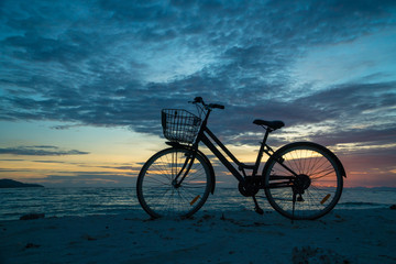 Fototapeta na wymiar Sunset silhouette of vintage bicycle on the beach 