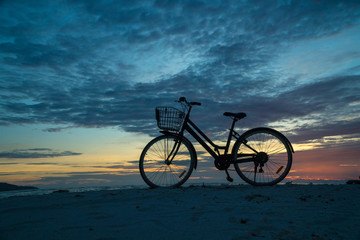 Fototapeta na wymiar Sunset silhouette of vintage bicycle on the beach 