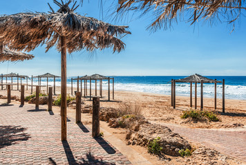 sun umbrellas made from palm leaves on the beach by the sea landscape background