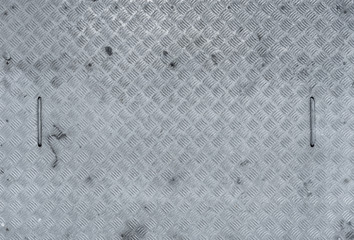 View from above of a galvanized, rectangular manhole cover made of checker plate with two handles,...