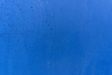 Blue painted concrete wall of a retaining wall in an industrial building, with cracks